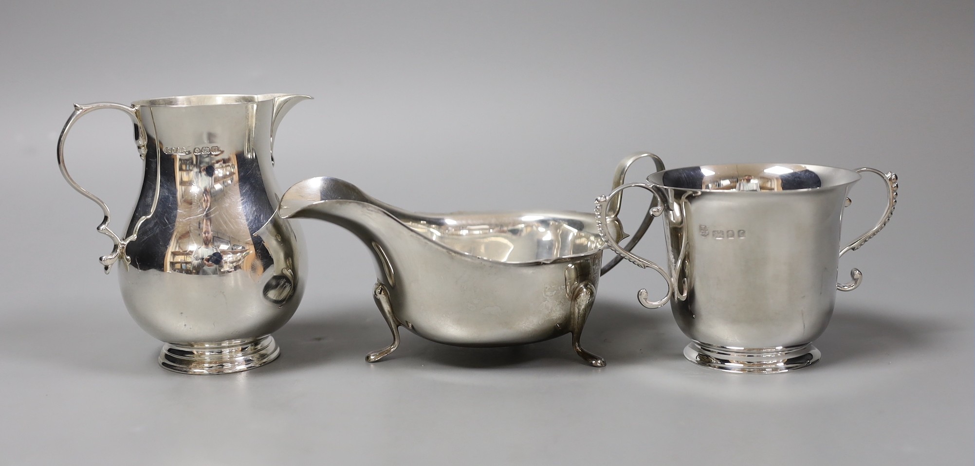 A small silver jug, Birmingham 1946 by Thomas Ducrow & Sons, together with a silver two handled cup, London 1973 by Tessiers Ltd and a silver sauceboat, 12oz.